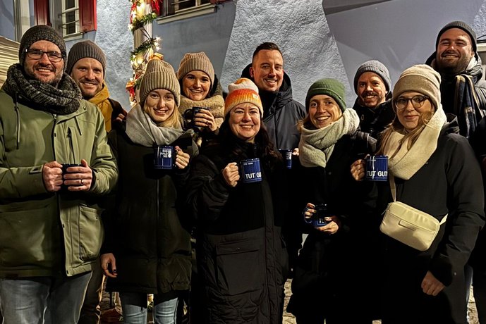 Weihnachtsfeier mit Lichterglanz Gruppe von Menschen bei einer festlichen Veranstaltung im Freien, mit rotem Schirm und Lichterdekoration.