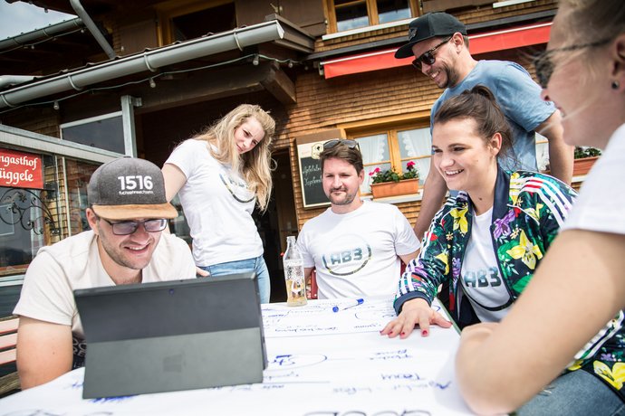 Arbeitende Gruppe AB3 Kollegen im Ausflugslokal in den Alpen vor dem Tablet beim Brainstorming