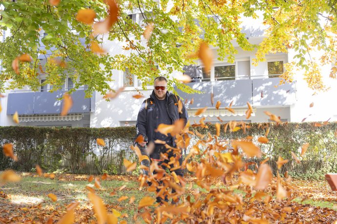 Herbstliche Ruhezone im Wohnumfeld Zwei Personen sitzen auf einer Parkbank unter herbstlich gefärbten Bäumen.