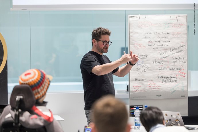 Vortrag über Barrierefreiheit Marvin Lang hält einen Workshop im Hintergrund steht Whiteboard mit vielen Stichpunkten