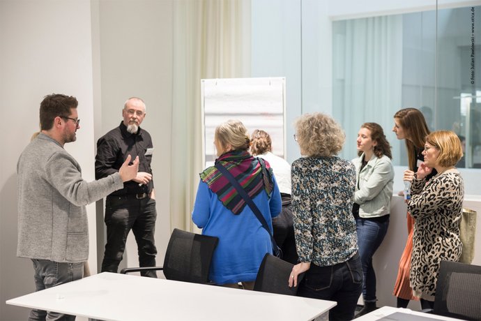 Interaktiver Vortrag auf dem Barcamp Eine Gruppe an Menschen tauschen sich vor einem Whiteboard aus