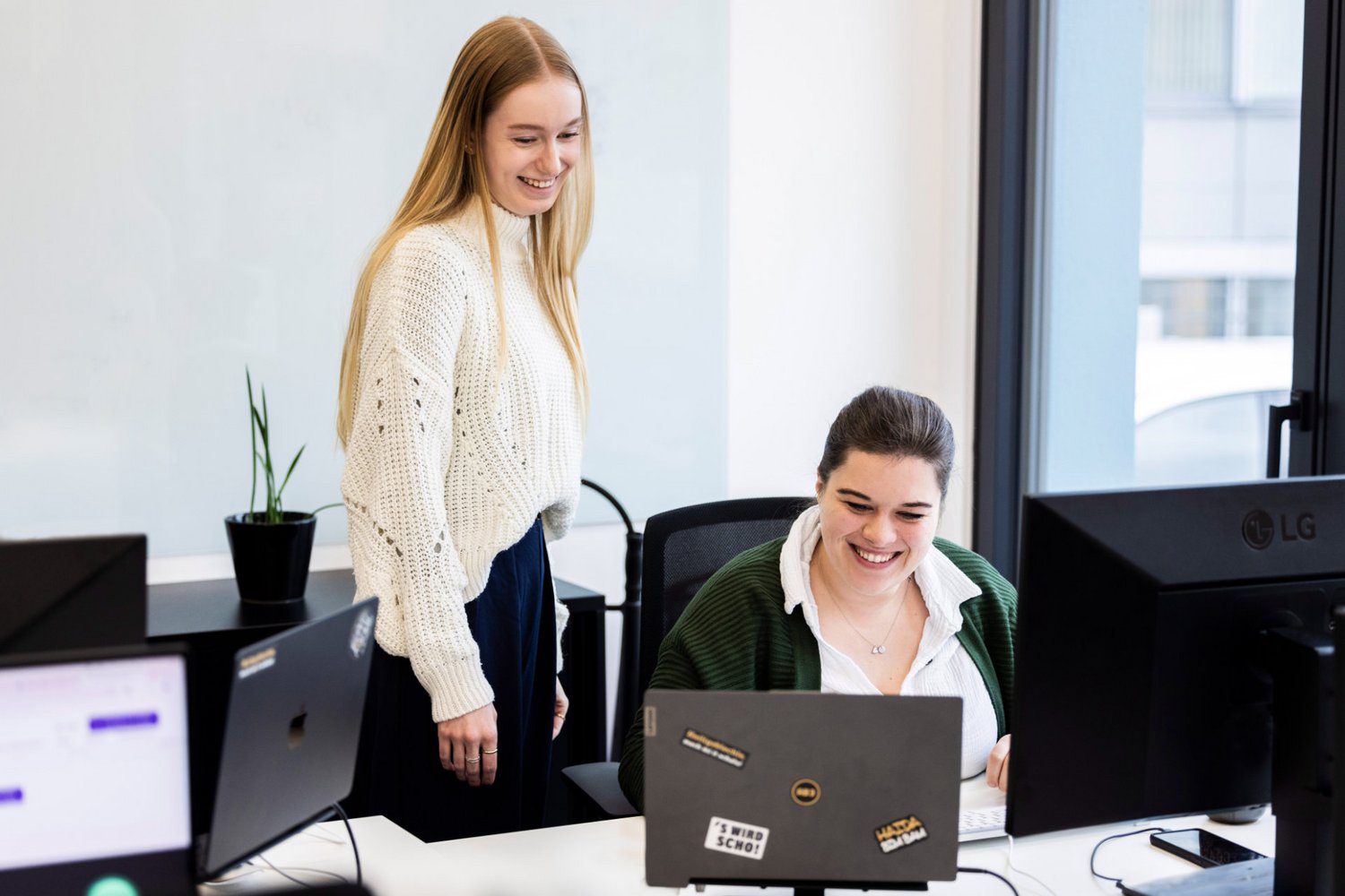 Kolleginnen bei Alpenblickdrei Zwei Kolleginnen arbeiten am Schreibtisch bei Alpenblickdrei