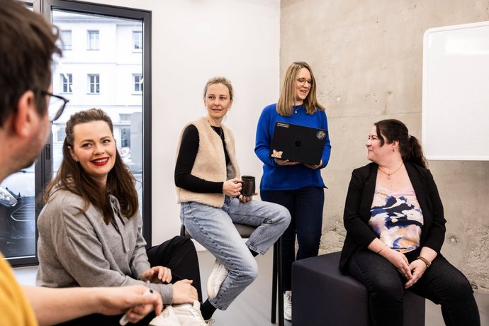 Brainstorming bei Alpenblickdrei Fünf Mitarbeitende der Alpenblickdrei Werbeagentur posieren gemeinsam beim Brainstorming