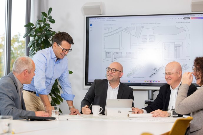 Besprechung im SWG-Konferenzraum Meeting mit mehreren Personen an einem Konferenztisch, moderne Büroatmosphäre.