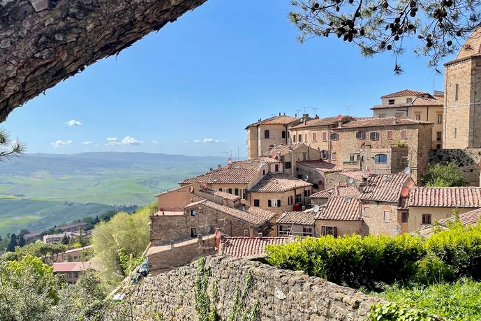 Blick auf das mittelalterliche Volterra in der Toskana Panoramablick auf die Altstadt von Volterra, mit ihren steilen Gassen, typisch toskanischen Gebäuden und roten Ziegeldächern, umgeben von der grünen Hügellandschaft.