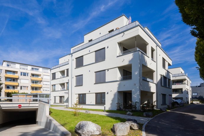 Neubauprojekt der SWG in Friedrichshafen Modernes, mehrstöckiges Wohnhaus bei Sonnenschein mit Balkonen und Flachdach.