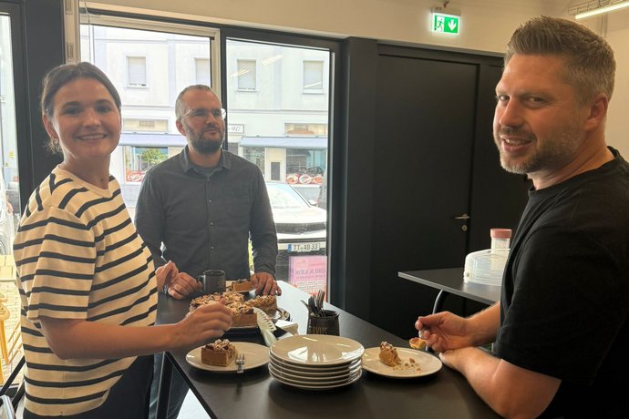 Gesprächsrunde beim After-Work-Treffen Drei Personen unterhalten sich entspannt an einem Stehtisch in einem modern eingerichteten Raum.